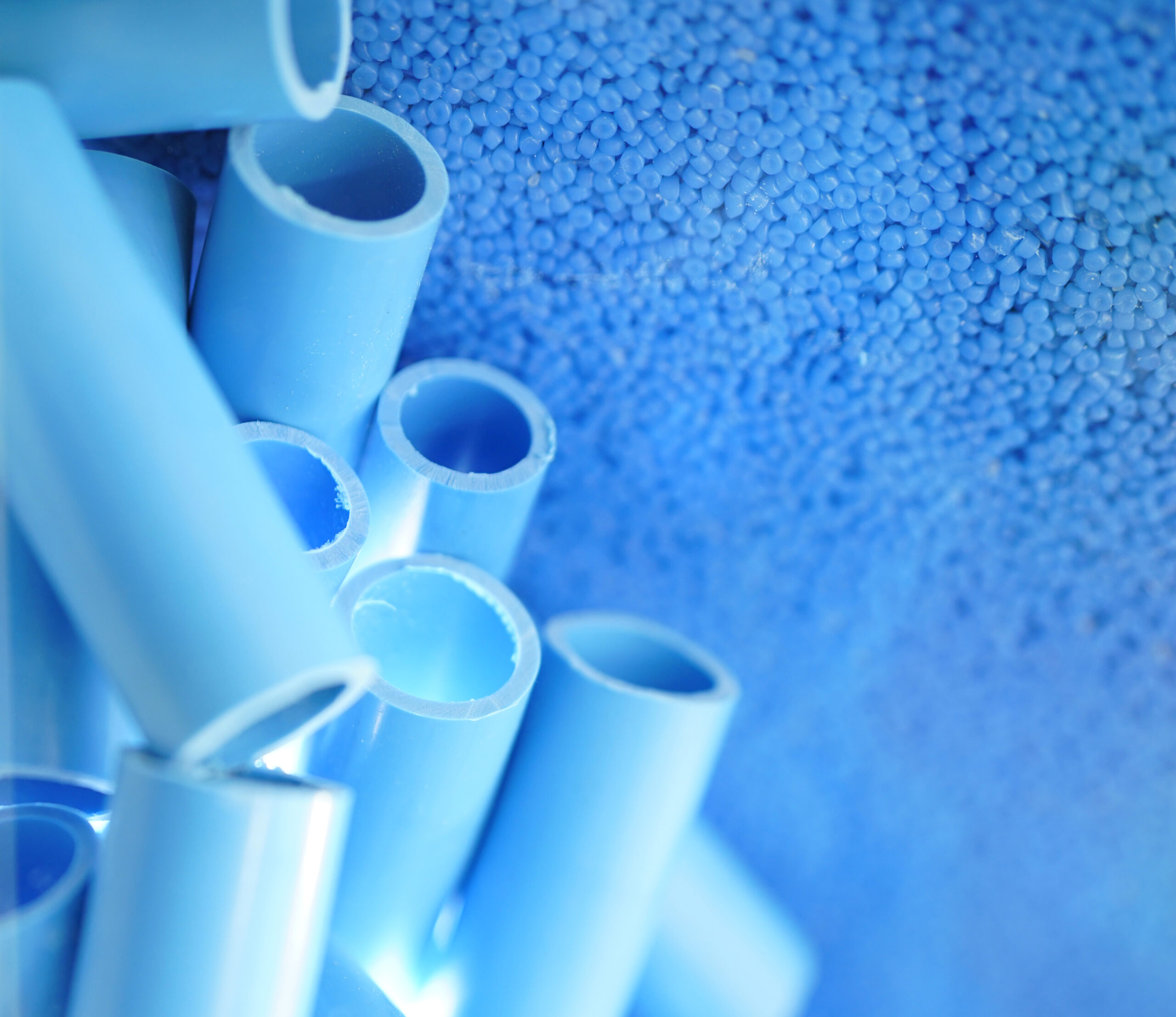 Blue pipe and plastic polymer pellets raw material for blue pvc pipe production. Industrial plastic resin. Chemical polymer granules. Thermoplastic. Plastic from petrochemical and compound extrusion.