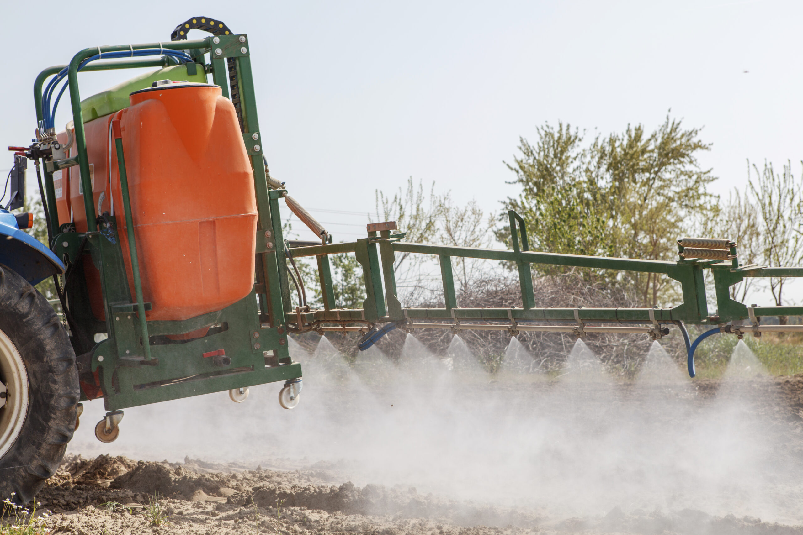 Tractor spraying wheat field with sprayer